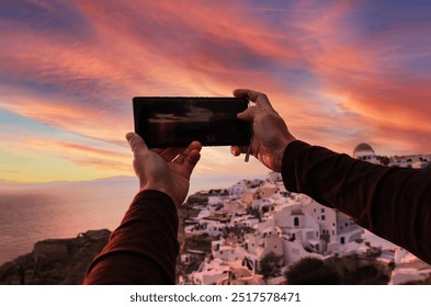 Man hand backpack using smartphone take picture at sunset View scene of blue church dome in Oia village,Santorini,Greece