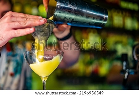 man hand bartender pouring cocktail in glass on the bar counter
