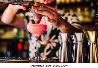 man hand bartender pouring pink cocktail in glass on the bar counter - Shutterstock ID 2208750049