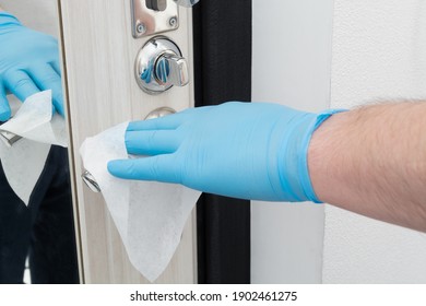 Man hand in blue glove cleaning door knob with disposable napkin Quarantine time - Shutterstock ID 1902461275