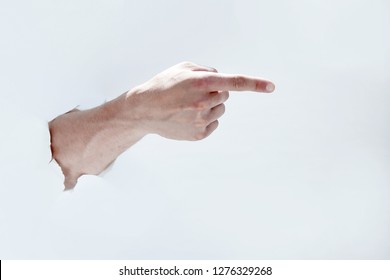 man hand breaking through the paper and pointing to a copy of th
