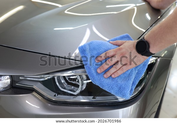 Man hand cleaning car and drying vehicle with\
microfiber cloth closeup