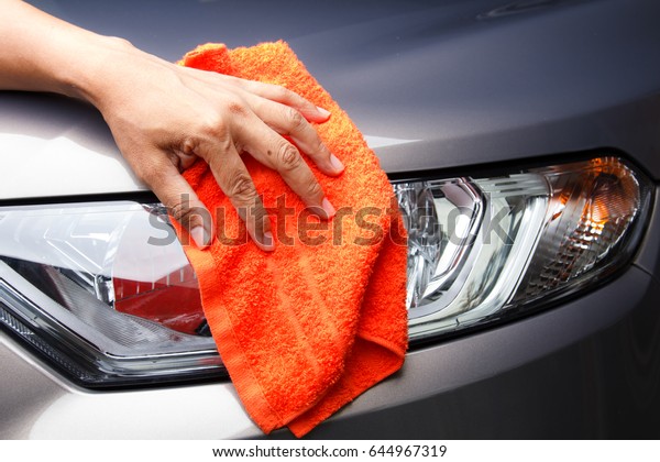 Man hand cleaning car with orange microfiber cloth\
after car wash