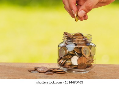 Man hand dropping coin and coins and jar. Saving money concept.  - Shutterstock ID 1314490463