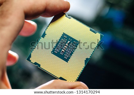 Man hand IT engineer holding against technological motherboard background new professional golden CPU processor  with thousands of pins and transistors