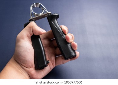 A man hand exercised with hand grip on a dark color background. - Shutterstock ID 1953977506