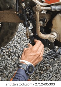 Man hand with focused concentration performs maintenance and repair on motorcycle part. close up view of mechanic working outdoor on bike brake system