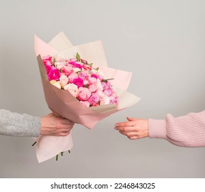 Man hand giving roses flowers bouquet to woman on grey background. Valentines or mothers day consept. - Powered by Shutterstock