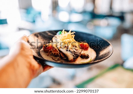 man hand hold Fried fillet dorado fish with tomatoes, lemon and sauce on plate