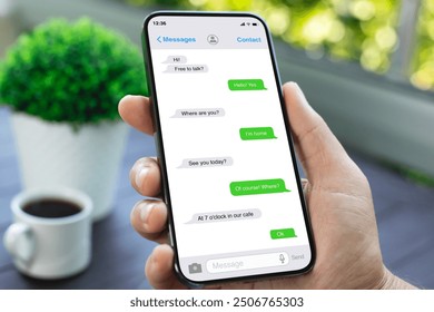 man hand hold phone with app messenger on the screen background cafe
