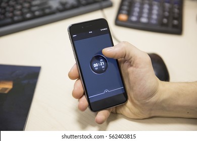 Man Hand Holding Black Mobile Phone On The Desktop Background In The Office.timer