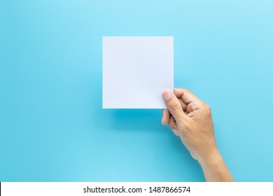 Man Hand Holding Blank Card Paper Sheet Isolated On Blue Background With Copy Space.