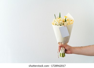 Man Hand Holding Bouquet Of White And Yellow Daffodils On White Background. Copy Space For Text.