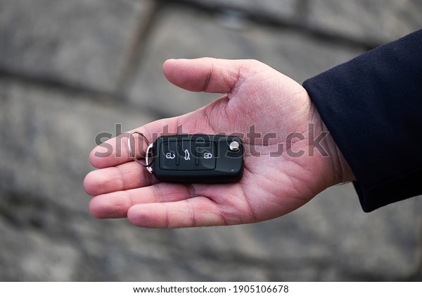 Man hand holding a car key. New\
car sell, auto showroom, car sale deal concepts. Black car\
key.
