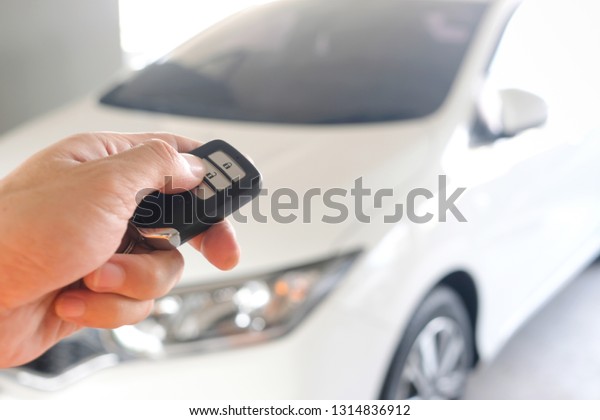 Man hand holding the car remote, he push the\
remote control to open the car\
door