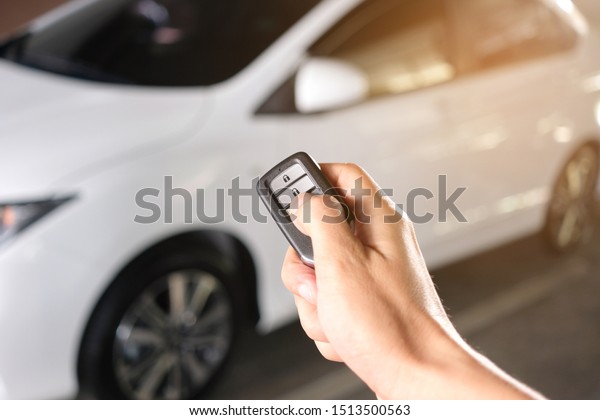 Man hand holding the car remote, he push the\
remote control to open the car\
door
