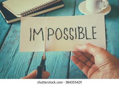 man hand holding card with the text impossible, cutting the word im so it written possible. success and challenge concept. retro style image
 - Shutterstock ID 384355429