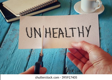 man hand holding card with the text unhealthy, cutting the word un so it written healthy. retro style image
 - Shutterstock ID 395917405
