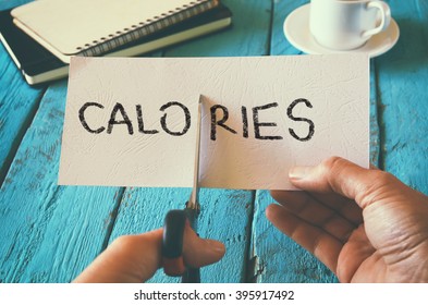 man hand holding card with the word calories. cutting calories and costs concept. retro style image