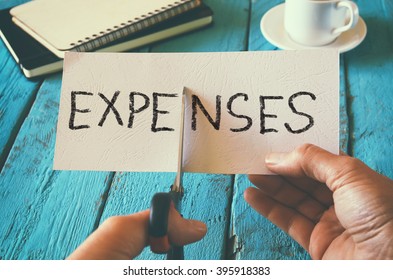 man hand holding card with the word expenses. cutting expenses and costs concept. retro style image - Shutterstock ID 395918383
