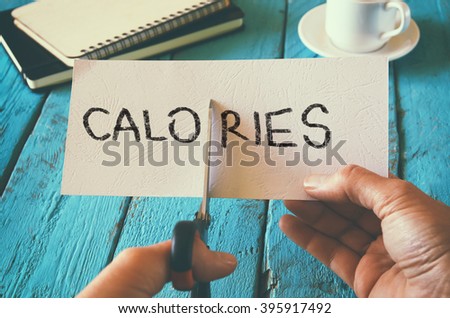 man hand holding card with the word calories. cutting calories and costs concept. retro style image