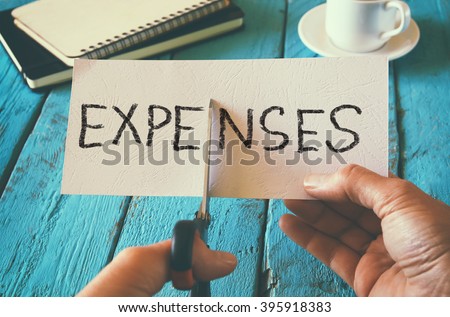 man hand holding card with the word expenses. cutting expenses and costs concept. retro style image