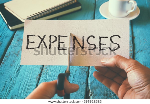 man hand holding card\
with the word expenses. cutting expenses and costs concept. retro\
style image