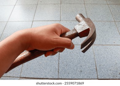 Man hand holding a claw hammer, showcasing the classic tool for industrial manual labor, ideal for construction, woodworking, and repair tasks - Powered by Shutterstock