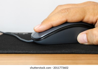 A Man Hand Holding A Computer Mouse Over A Black Mousepad.