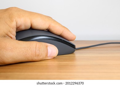 A Man Hand Holding A Computer Mouse Over A Black Mousepad.