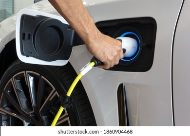 Man hand is holding Electric car charging connect to elecric car on charge station, Electric mobility environment friendly 	