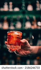 Man Hand Holding A Glass Of Negroni Cocktail In A Bar