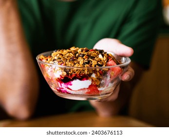 A man hand holding granola bowl with dried oats, nuts seeds muesli, cubes watermelon tropical fruit and plain Greek yogurt. Healthy breakfast smoothie Thai Asian style summer refresh recipe. Closed up - Powered by Shutterstock