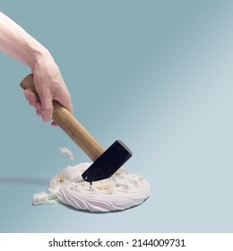 A Man Hand Holding Hammer Smashed  Sweet Meringue Pavlova Cake. Sky Blue Background.