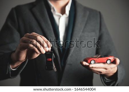 man hand holding key with car model