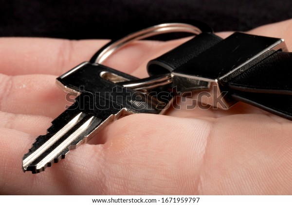 Man hand\
holding keys with keyring for\
motorbike