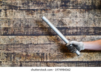 Man Hand Holding Metal Rod On Wood Background