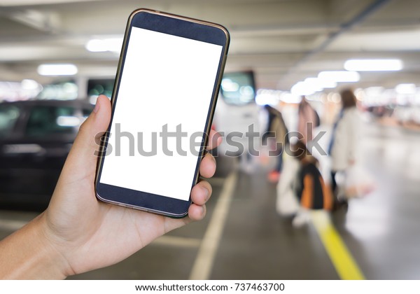 Man hand\
holding mobile smart phone,tablet,cellphone over Blur of  parking\
area with perspective view,blurry image with bokeh of Car park\
interior for background usage.vintage\
photo