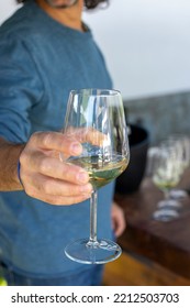 Man Hand Holding Out A Wine Glass In A Celebration. Closeup.