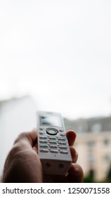 Man Hand Holding Outdoor Home Office White Cordless Phone Dialing A Number On The White Keyboard Trying To Reach Base Signal