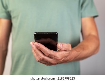 Man Hand Holding Phone. Male Looking At Smartphone Screen For Video Call Or Reading Message, Checking Weather, Bank Balance, Surfing Internet. High Quality Photo