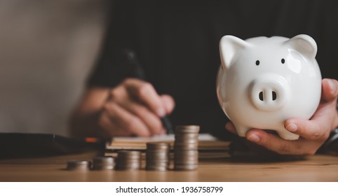 Man hand holding piggy bank on wood table, saving money wealth and financial concept, Business, finance, investment, Financial planning.