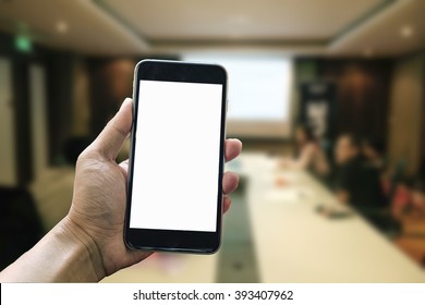 A Man Hand Holding Smart Phone Device In Meeting Room