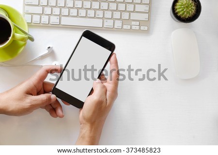 Man hand holding smart phone with white blank empty screen on white desk table.