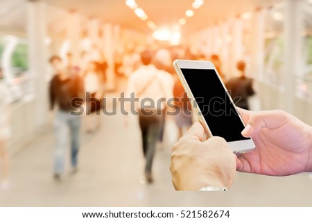 Man hand holding smart phone with people walking street blur background.