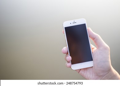 Man hand holding smartphone against on smooth background. - Powered by Shutterstock