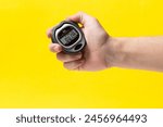 Man hand holding stopwatch on yellow background, closeup. Time management concept