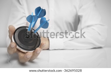 Man hand holding a target with three darts hitting the center over white background. Concept of personal coaching success and objective attained