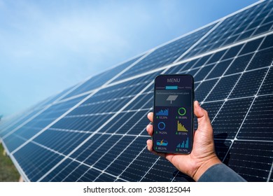 Man Hand Holding The Telephone For Monitoring Performance In Solar Power Plant(solar Cell). Alternative Energy To Conserve The World's Energy, Photovoltaic Module Idea For Clean Energy Production.