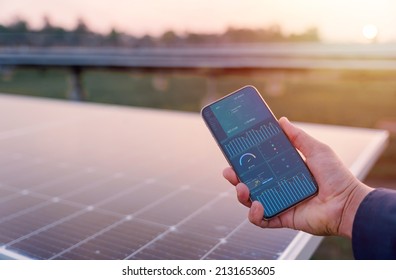 Man hand holding the telephone for monitoring performance in solar power plant(solar cell). Alternative energy to conserve the world's energy, Photovoltaic module idea for clean energy production.